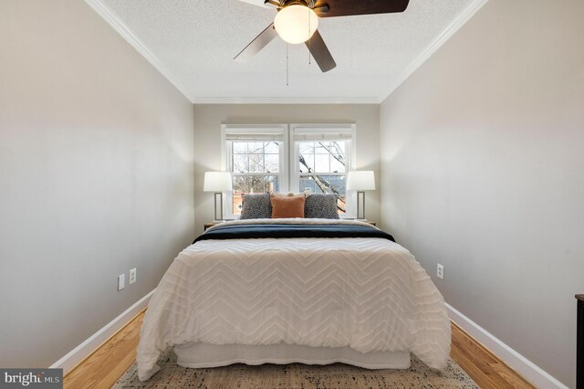 bedroom with baseboards, wood finished floors, and crown molding