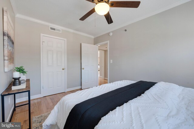 bedroom featuring visible vents, baseboards, light wood-style floors, and crown molding