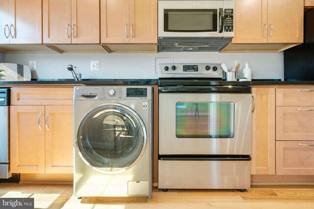 kitchen with washer / clothes dryer, dark countertops, appliances with stainless steel finishes, and light brown cabinets