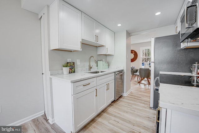 kitchen featuring a sink, stainless steel appliances, light wood-type flooring, and white cabinetry