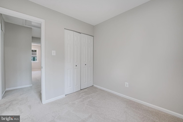 unfurnished bedroom with baseboards, carpet floors, and a closet