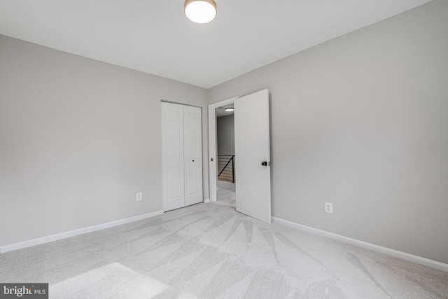 spare room with baseboards and light colored carpet