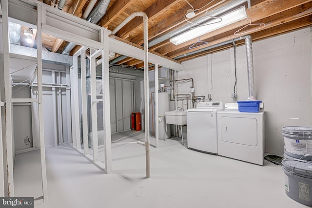 unfinished basement featuring a sink, independent washer and dryer, and water heater