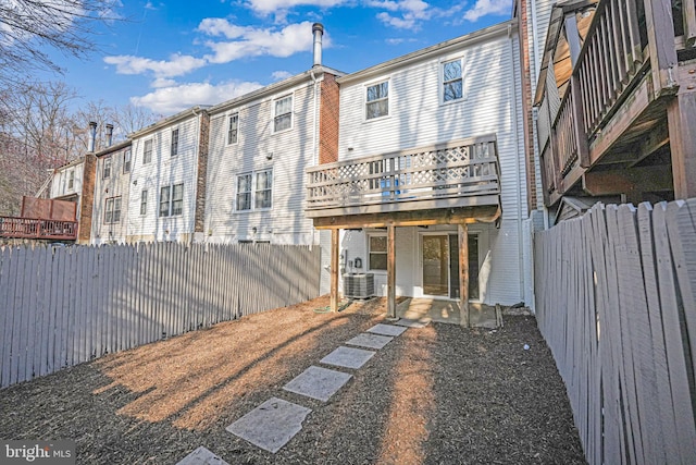 rear view of property with a deck, central air condition unit, and a fenced backyard