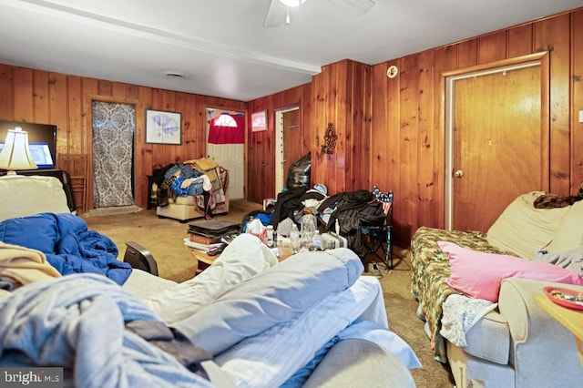 carpeted living area featuring visible vents, ceiling fan, and wood walls