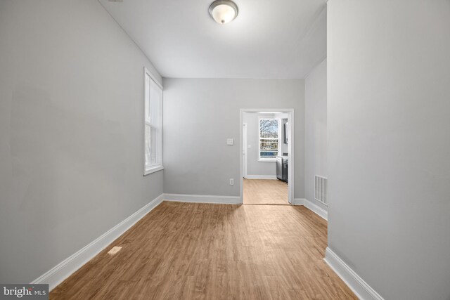 unfurnished room featuring light wood-style floors, visible vents, and baseboards