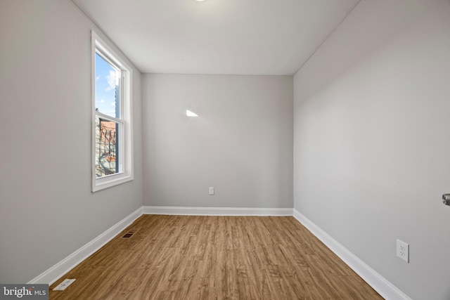 unfurnished room featuring visible vents, baseboards, and wood finished floors