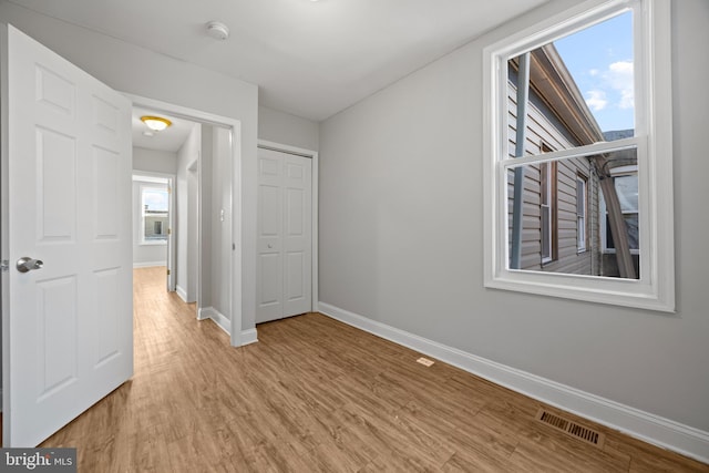 unfurnished bedroom with light wood finished floors, baseboards, visible vents, and a closet