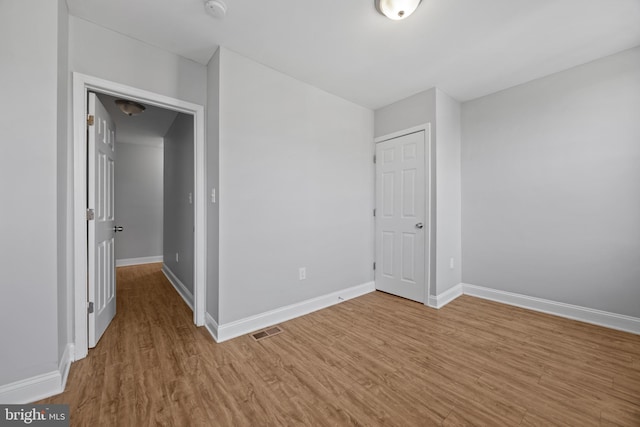 unfurnished bedroom featuring visible vents, baseboards, and wood finished floors