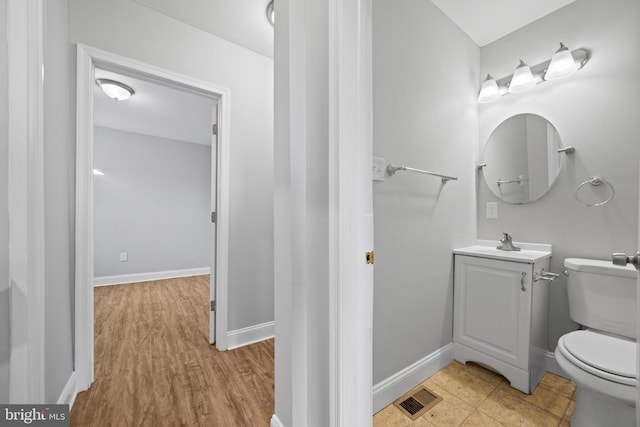 half bath with toilet, baseboards, visible vents, and vanity