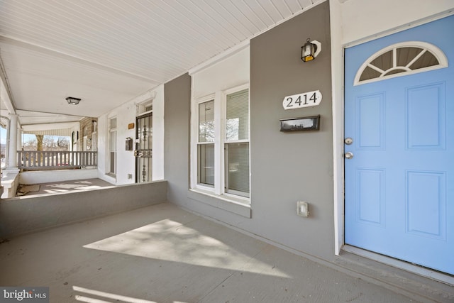 property entrance featuring covered porch and stucco siding