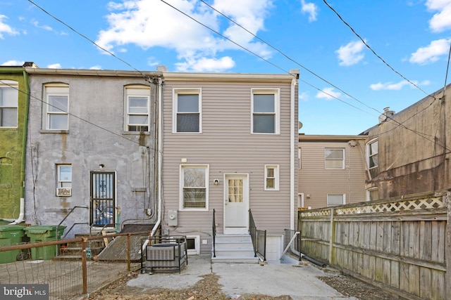 rear view of property featuring entry steps and fence