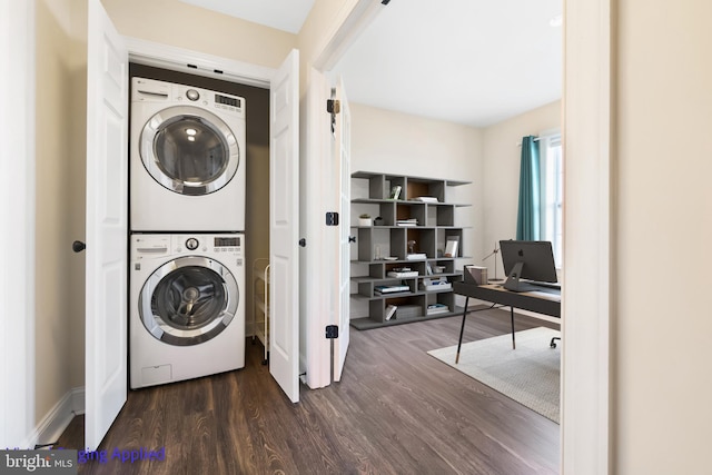 clothes washing area with wood finished floors, laundry area, and stacked washer / dryer