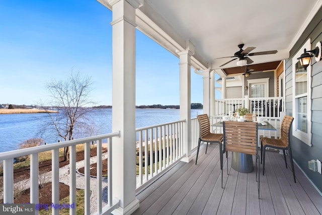 wooden deck with outdoor dining area, a water view, and ceiling fan