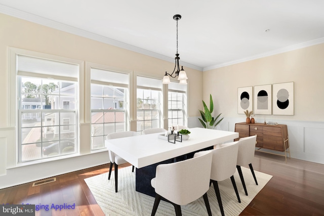 dining room featuring plenty of natural light, hardwood / wood-style floors, crown molding, and a wainscoted wall