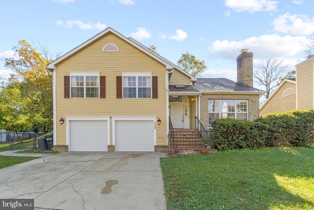 split level home featuring a chimney, an attached garage, a front yard, fence, and driveway