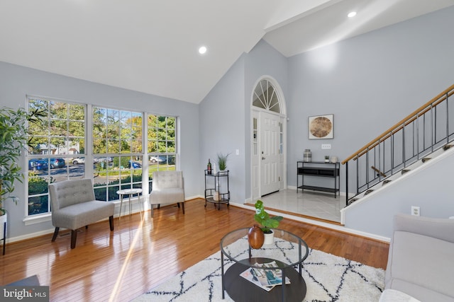 living room featuring high vaulted ceiling, hardwood / wood-style flooring, recessed lighting, baseboards, and stairs