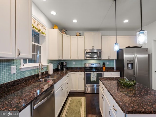 kitchen with dark wood-style flooring, pendant lighting, stainless steel appliances, decorative backsplash, and a sink