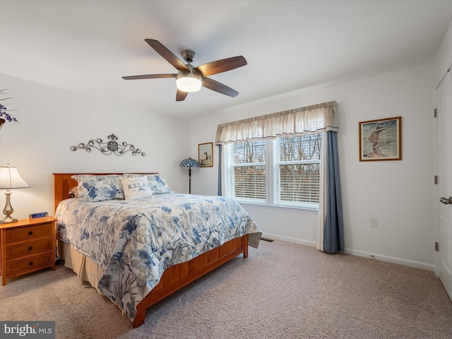 bedroom with a ceiling fan, light carpet, and baseboards