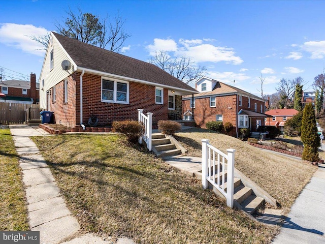 bungalow with a front yard, brick siding, and fence