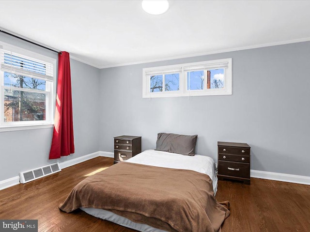 bedroom featuring crown molding, wood finished floors, visible vents, and baseboards