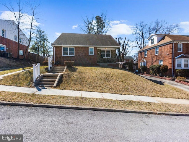 view of front of home with central AC, brick siding, a front yard, and fence