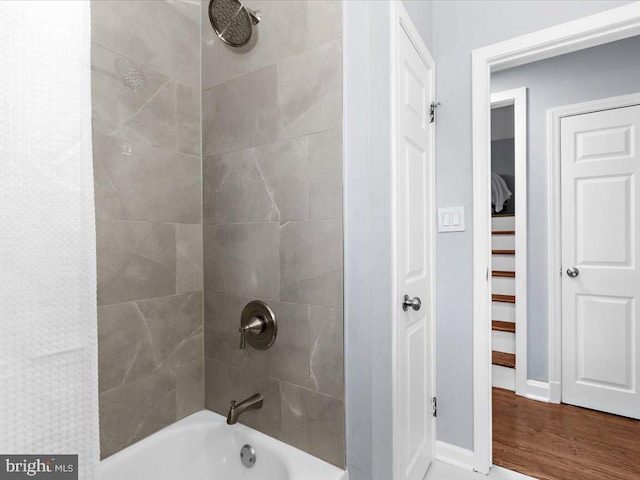 bathroom with shower / bathtub combination, wood finished floors, and baseboards