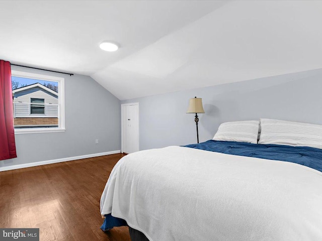 bedroom with lofted ceiling, baseboards, and wood finished floors