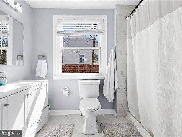 bathroom with marble finish floor, plenty of natural light, baseboards, and vanity