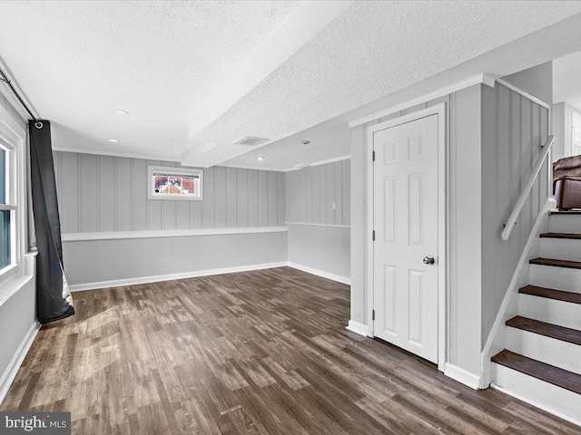 basement with baseboards, visible vents, wood finished floors, stairs, and a textured ceiling