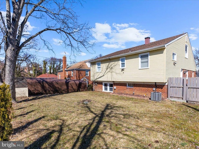 back of property with a yard, central AC, fence, and a chimney