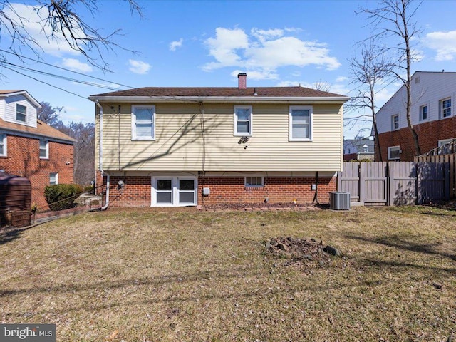 rear view of house featuring a yard, brick siding, fence, and a chimney