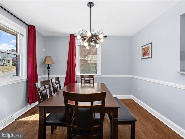 dining space with an inviting chandelier, baseboards, visible vents, and wood finished floors