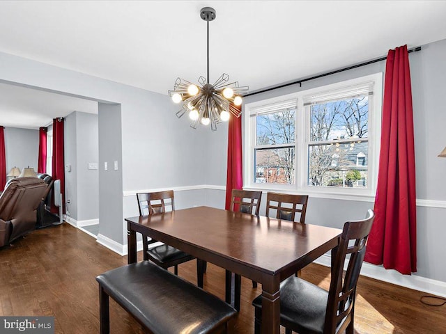 dining area with dark wood-type flooring, an inviting chandelier, and baseboards