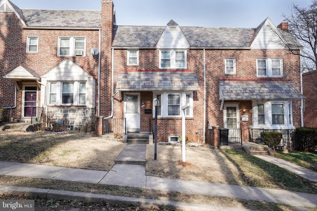 townhome / multi-family property with brick siding, a chimney, and a high end roof