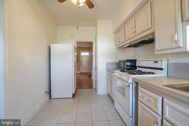 kitchen featuring white appliances, light countertops, under cabinet range hood, backsplash, and light tile patterned flooring