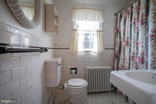 bathroom featuring toilet, a wainscoted wall, tile walls, tile patterned floors, and radiator heating unit