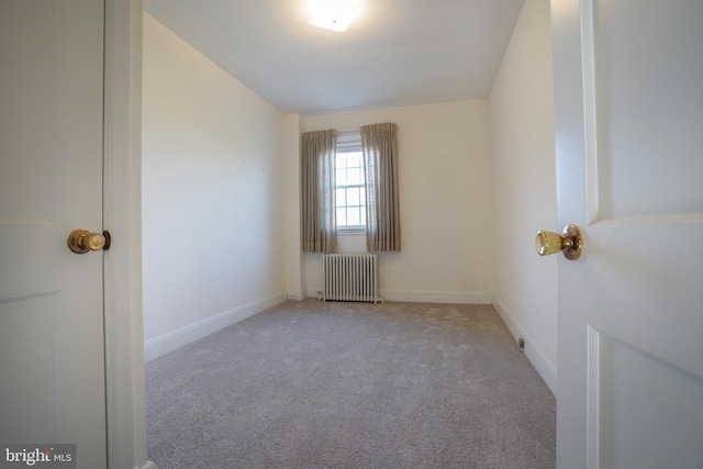 carpeted spare room featuring radiator heating unit and baseboards