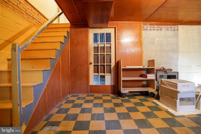 interior space featuring concrete block wall, wooden ceiling, dark floors, and stairway