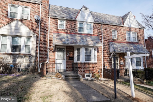 townhome / multi-family property featuring a high end roof and brick siding