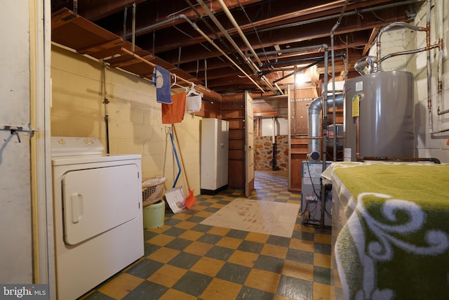 unfinished below grade area featuring water heater, concrete block wall, washer / dryer, and tile patterned floors