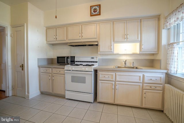 kitchen featuring white gas stove, under cabinet range hood, radiator heating unit, a sink, and stainless steel microwave