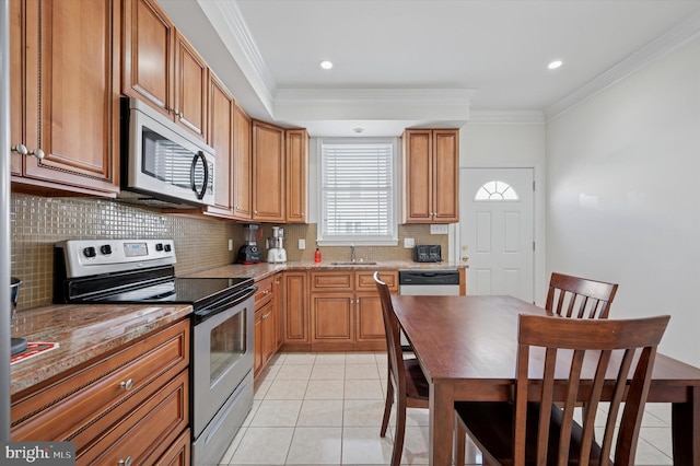 kitchen featuring light tile patterned floors, stainless steel appliances, ornamental molding, and a sink