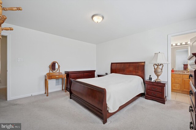 bedroom with baseboards, connected bathroom, and light colored carpet