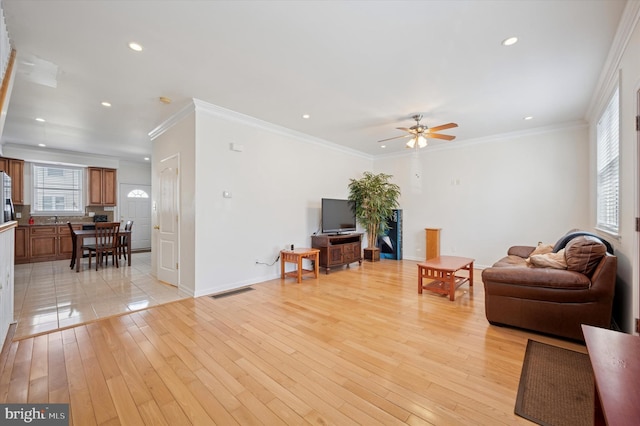 living room with recessed lighting, crown molding, light wood-style flooring, and baseboards