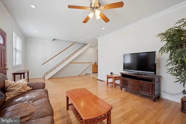 living area featuring ornamental molding, light wood finished floors, and stairs