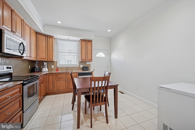 kitchen with light tile patterned floors, brown cabinetry, decorative backsplash, appliances with stainless steel finishes, and ornamental molding