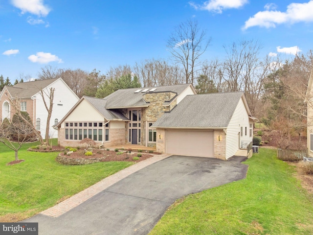 view of front of property with driveway, a front lawn, an attached garage, and stone siding