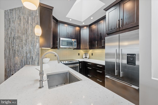 kitchen with a sink, tasteful backsplash, stainless steel appliances, dark brown cabinetry, and light stone countertops