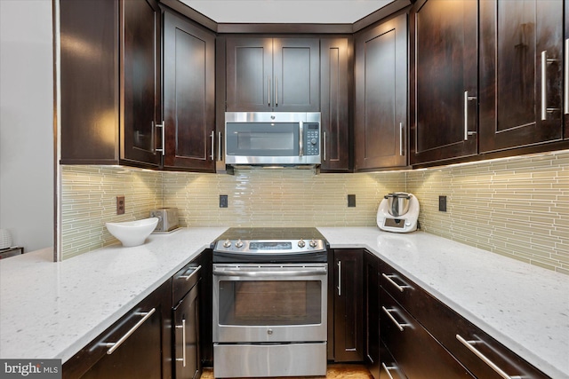 kitchen with dark brown cabinetry, light stone countertops, tasteful backsplash, and stainless steel appliances